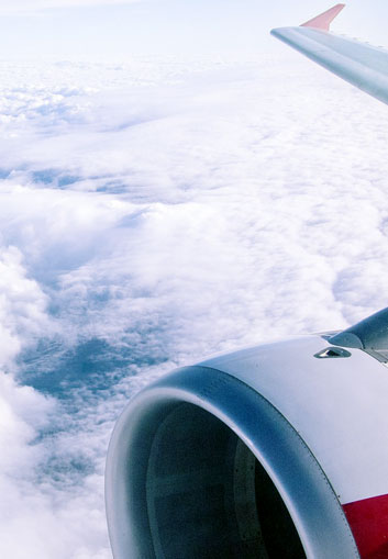 An airplane wing over blue cloudy sky